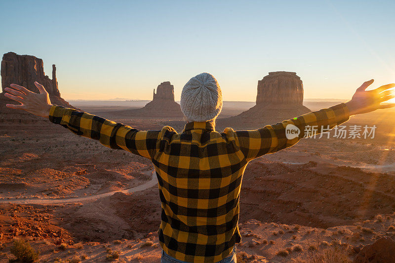 黎明时分，在纪念碑谷，一名男子举起手臂，拥抱在美国的旅行