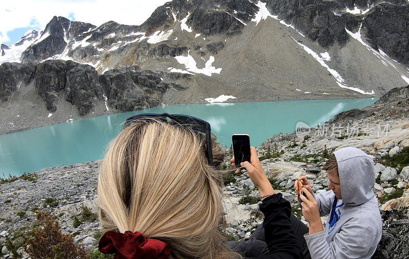 徒步者从山上的湖上方的巨石场拍照
