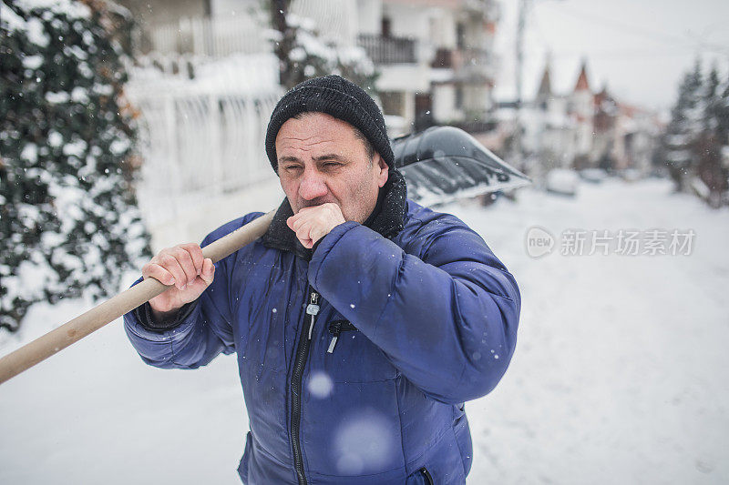 一位老人正在扫雪