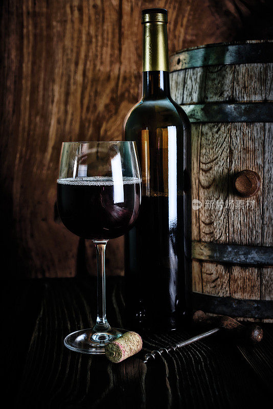 葡萄酒瓶，葡萄酒桶，葡萄酒杯与一个螺旋和软木塞射击在乡村纹理木制桌子。