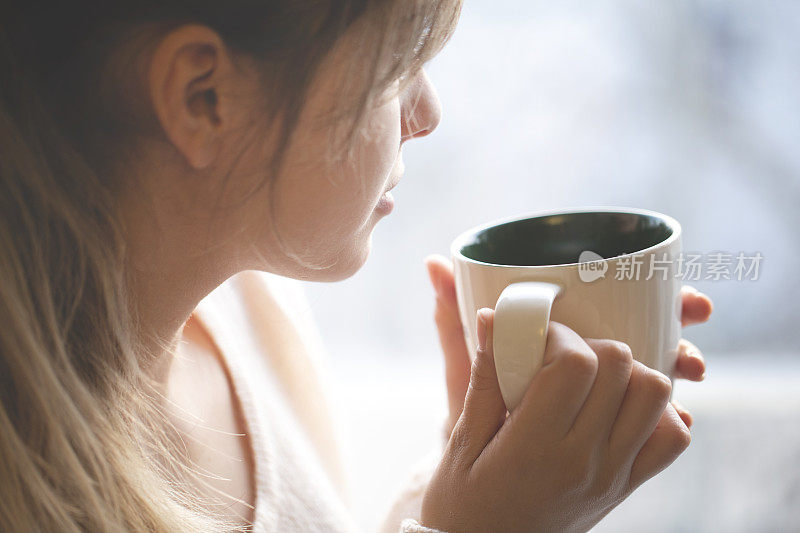 体贴的年轻女子拿着咖啡杯在家