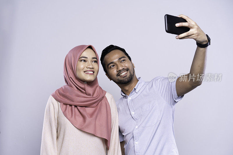 一对年轻的亚洲马来夫妇在手机上自拍