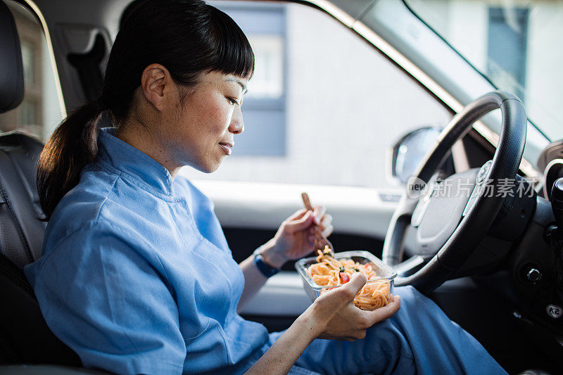 年轻的日本医护人员在车里吃午饭