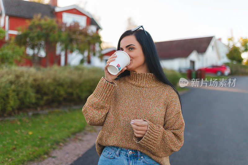 一个美丽的年轻黑发女人在郊区拿着咖啡杯的画像