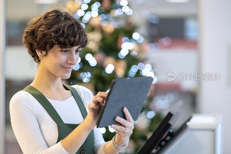 圣诞节，新年和一个女孩在圣诞树前拿着平板电脑