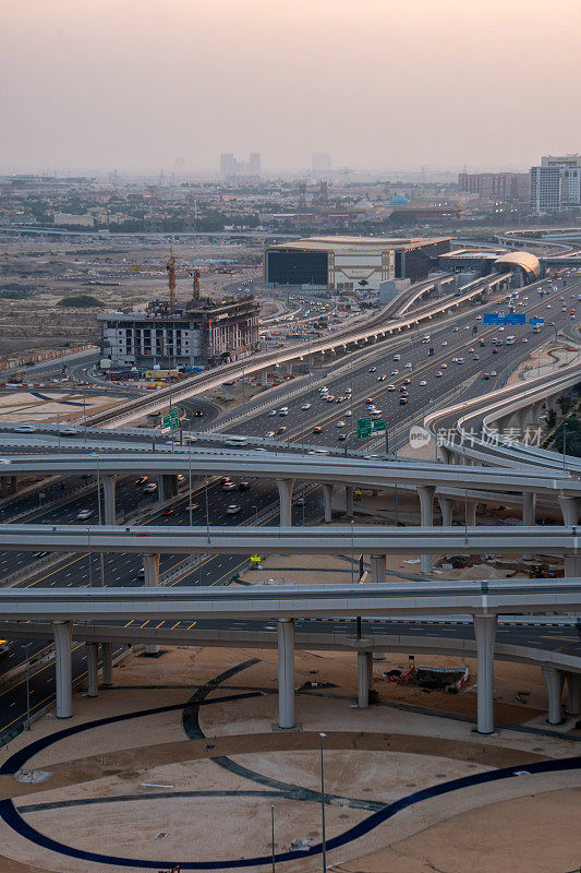 沙漠景观中的大型高速公路和立交公路，附近有建筑物，天空朦胧，污染严重。