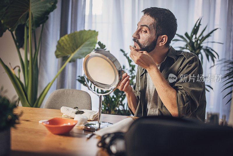 一名男子在面部护理过程中用化妆棉洗脸