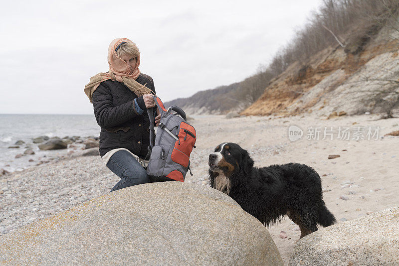 一个成熟的女人和她的家狗在波罗的海边休息。