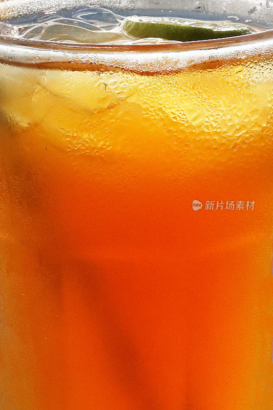全帧图像的玻璃杯柑橘橙无酒精饮料与冰块和酸橙片，凝结，重点在前景