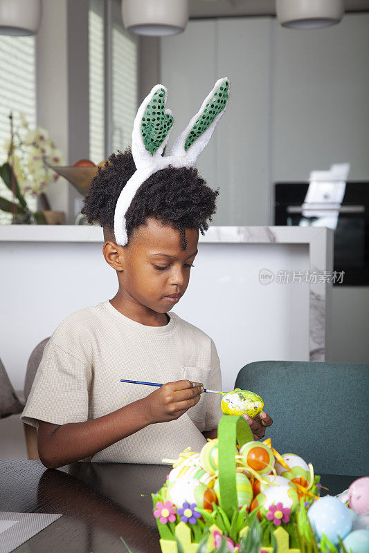 一个非裔美国男孩在厨房里装饰复活节彩蛋