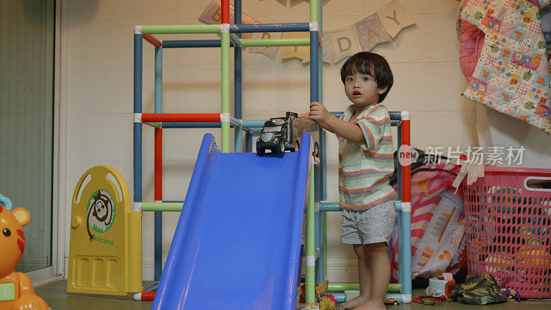 亚洲男孩喜欢玩卡车汽车滑滑梯。家里的操场。