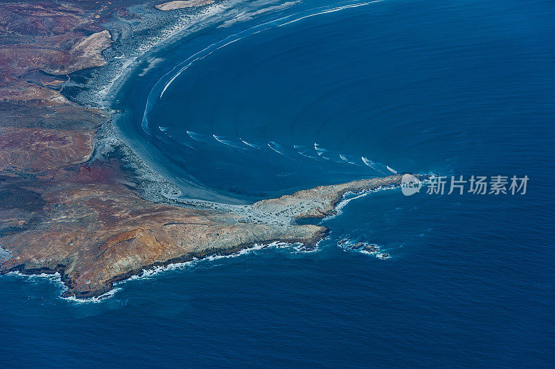 几组太平洋海浪撞击一小块陆地，造成波浪弯曲。下加利福尼亚南部，墨西哥。波变浅。