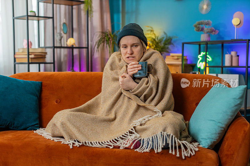 生病的不健康的女人冻僵了，感觉很糟糕，盖着温暖的毯子在家里喝茶