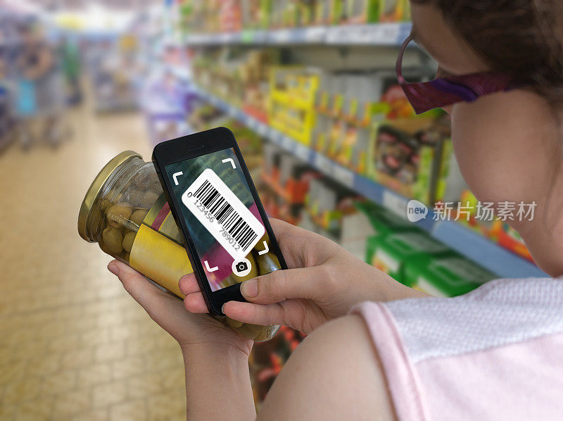 一位女士正在超市购物，并用智能手机扫描条形码。