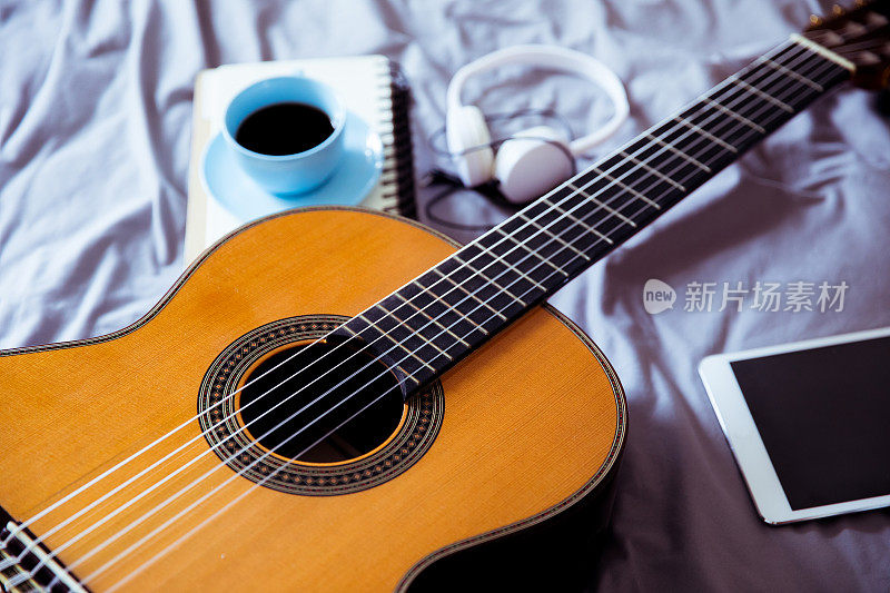 床上放着吉他和咖啡杯