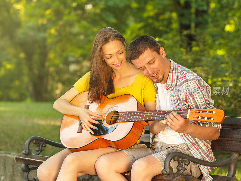一对年轻夫妇在公园里弹吉他