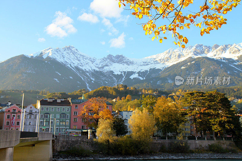 因斯布鲁克酒店的河岸建筑立面和田园诗般的秋天，北蒂罗尔雪山覆盖的卡温德尔山脉在日出，奥地利