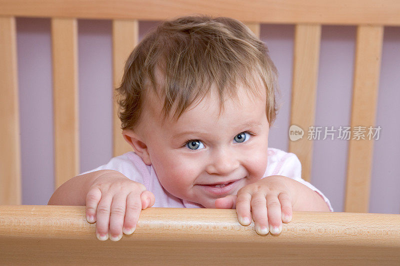 人-害羞的10个月大的女婴在婴儿床