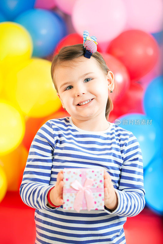 可爱的小女孩拿着礼品盒，微笑着