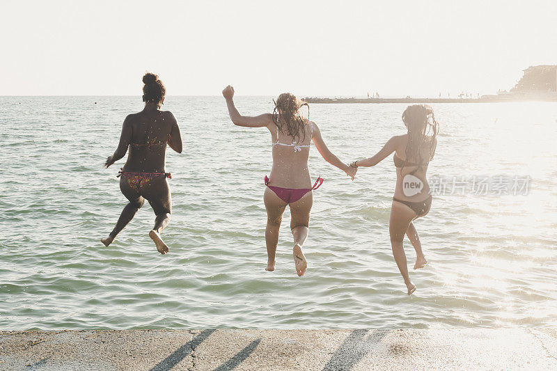 三个女人在夏天跳进海里