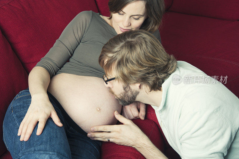 未来的爸爸亲吻怀孕的妈妈的肚子。