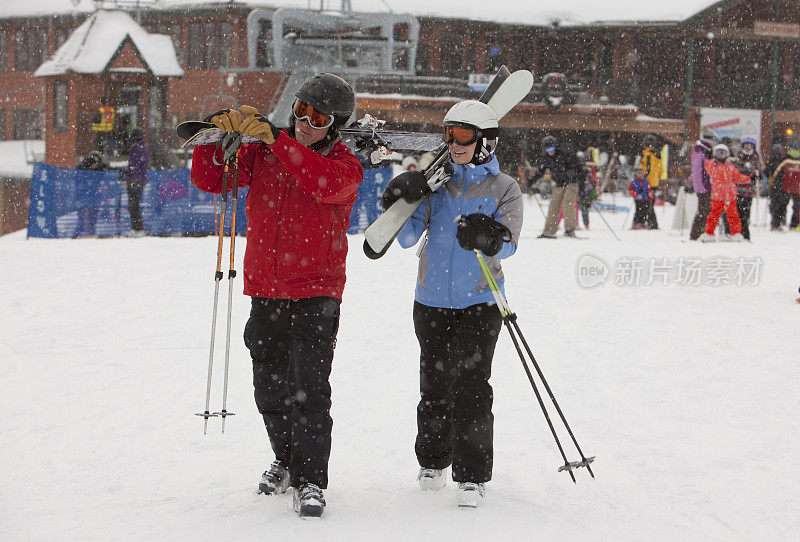 一对夫妇带着装备穿过滑雪村