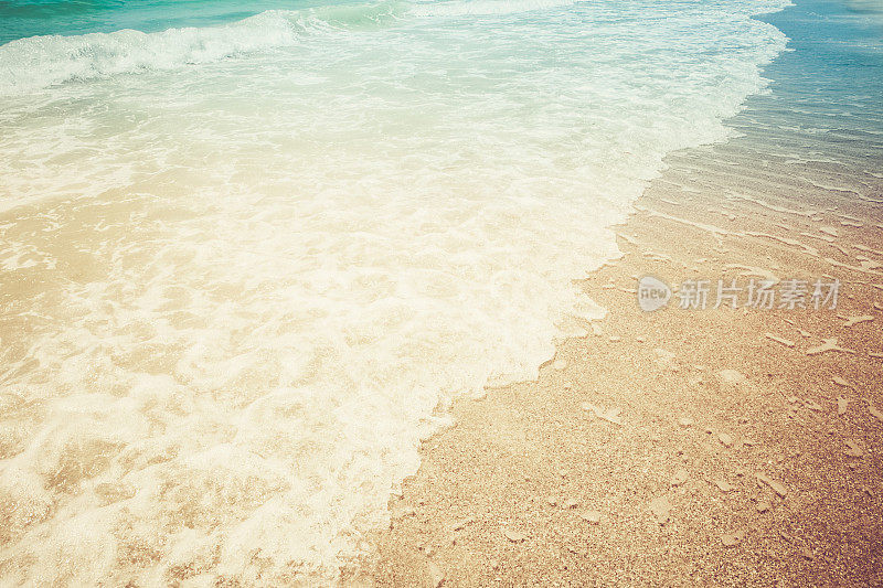 潮汐和海浪翻滚到阳光明媚的夏日海滩