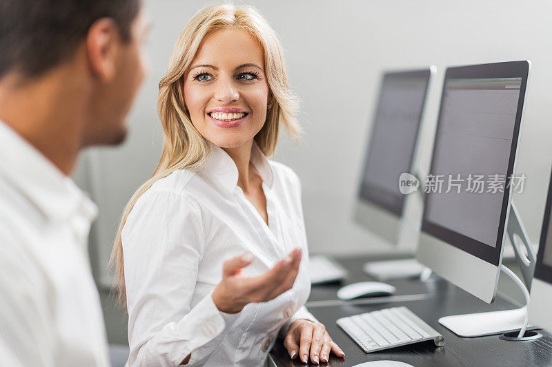 微笑的女商人在计算机课上和她的同事交谈。