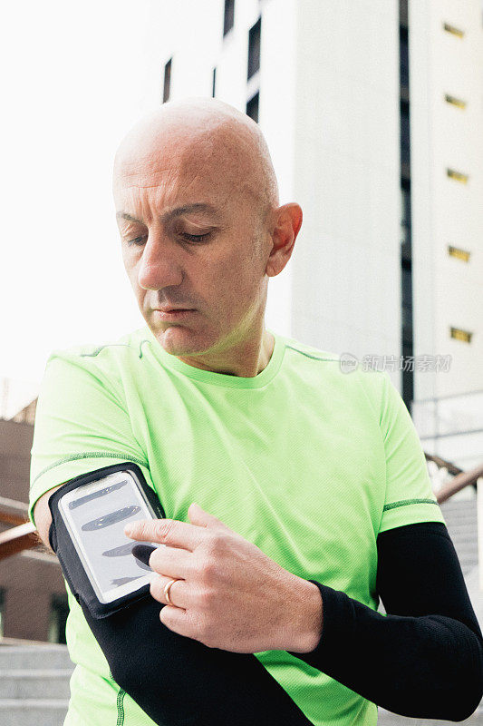 成熟男人在锻炼中使用智能手机佩戴腕带