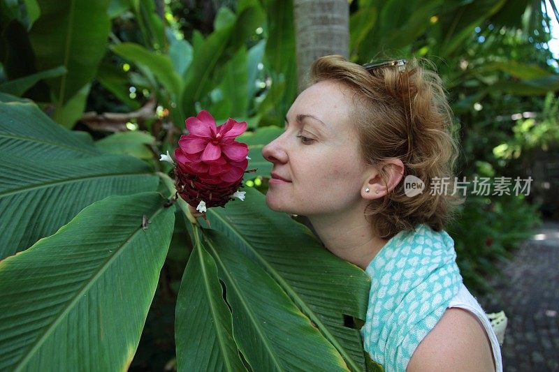 女孩闻着热带的花朵。