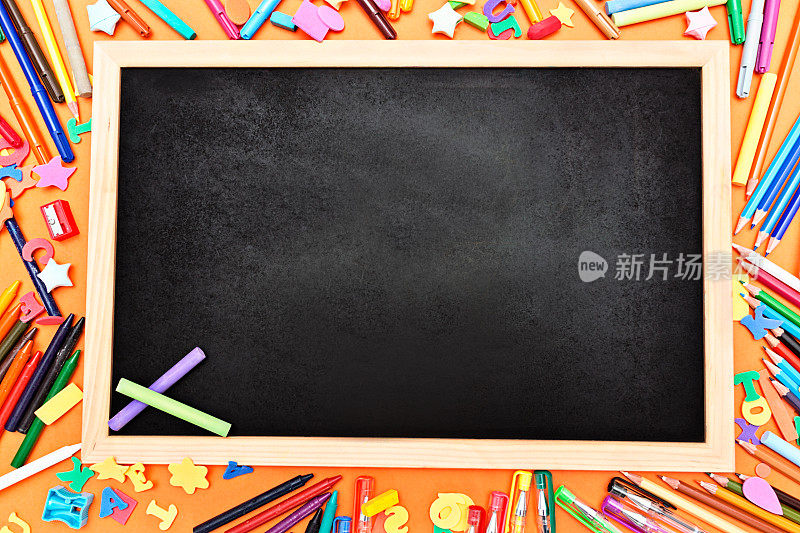 两支粉笔在空白的黑板上，旁边放着文具