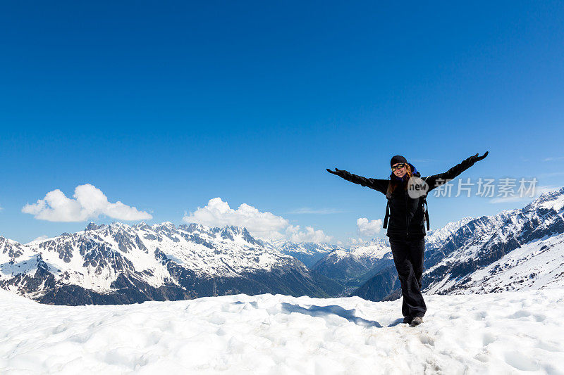 手臂举起的女人在山顶徒步旅行