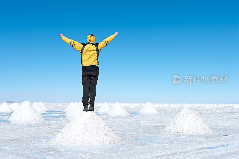 游客站在玻利维亚高原乌尤尼盐沼上