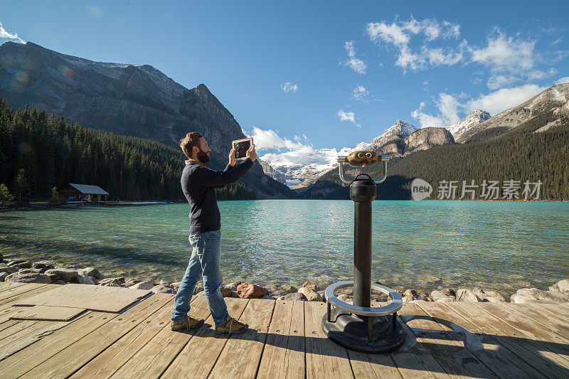 一名年轻人在路易斯湖用数码平板电脑拍摄风景