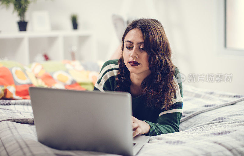 女人在床上用手机和笔记本电脑聊天