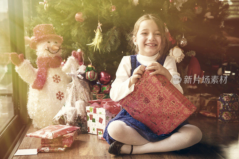 可爱的女孩打开她的圣诞礼物