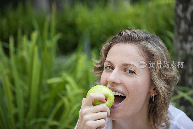 美丽的女人在吃青苹果