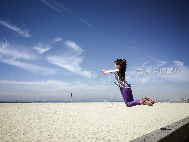 快乐的小女孩在空旷的海滩上跳起来