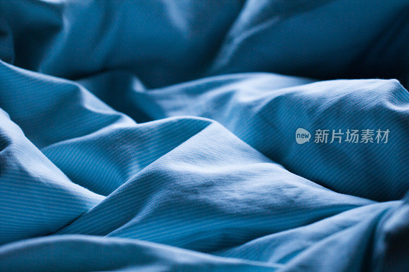 在柔和的早晨或傍晚浪漫的阳光下，轻轻地睡在蓝色的床单上
