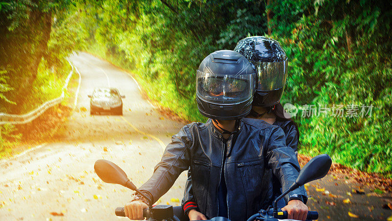 一对骑摩托车的夫妇在柏油路上骑摩托车