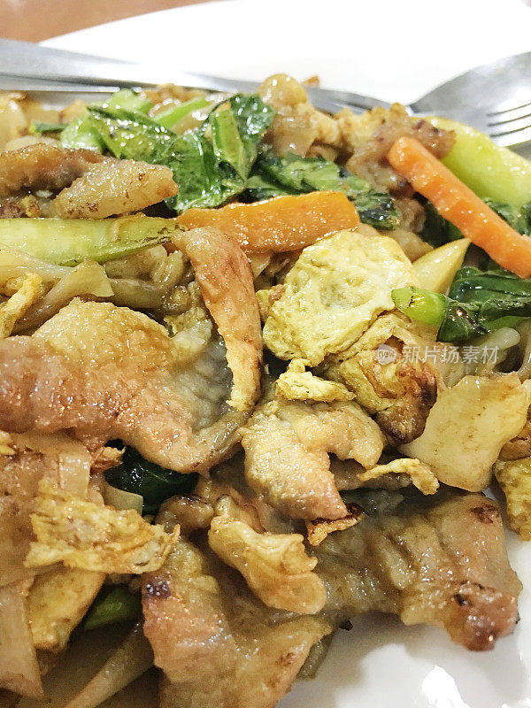 木桌上白底豆沙炒面和猪肉。泰国风格的食物。