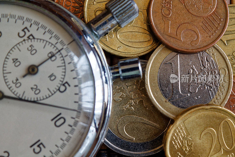 秒表和成堆的硬币放在木桌的背景上