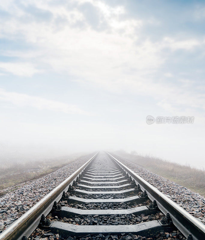 草地上的铁路，上面有雾和云