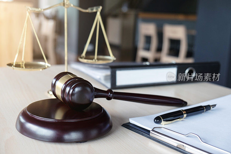 近距离展示正义的木槌和天平，在办公室的木桌上用纸报告案件，法律和正义的概念