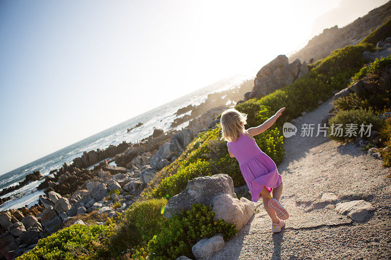 可爱的女孩在海边的小路上奔跑