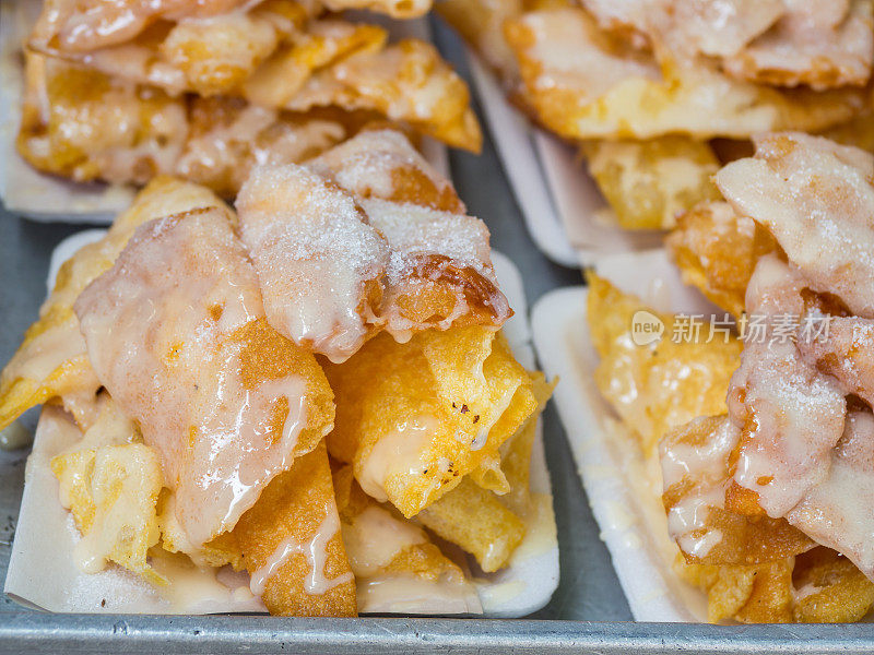 香脆的烤饼配甜炼乳和糖放在纸盘上。油炸烤肉是泰式甜点。泰国街头小吃和甜点。