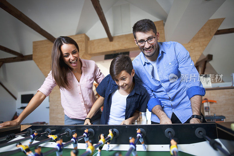 幸福微笑的家人一起玩桌上足球