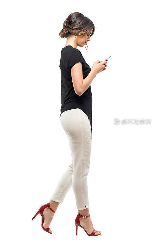 侧视图，忙碌的商务妇女在正装行走和打字的手机。