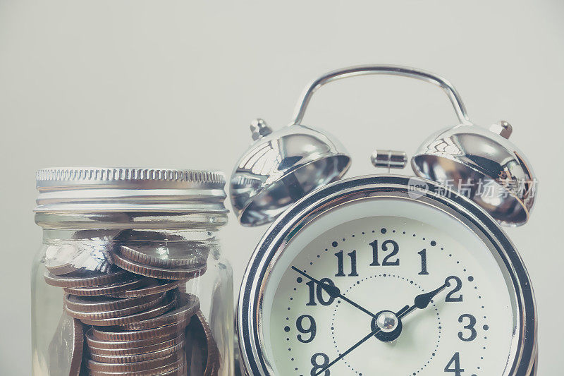钱硬币在罐子与时钟，概念节省金钱和时间管理