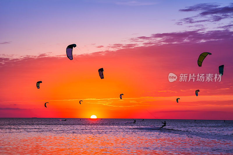 在美丽的夕阳下风筝冲浪。天空中有许多风筝的剪影。度假的本性。艺术照片。美丽的世界。